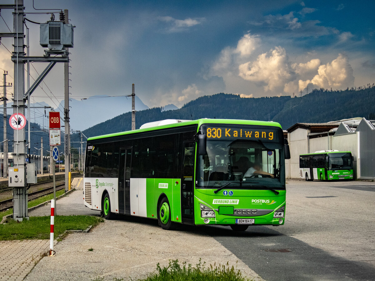 St. Michael. Dunkle Wolken über dem Murtal: Am 29.08.2024 steht der Postbus 16417 abfahrbereit als Linie 830 nach Kalwang im Bahnhof St. Michael.